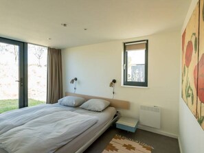 Une chambre à coucher avec un lit, une fenêtre, un radiateur et un tableau accroché au mur.