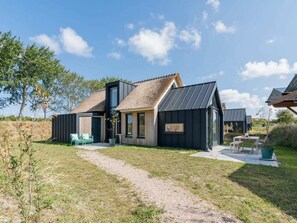 Une maison moderne avec un toit de chaume, une grande fenêtre et une allée pavée.