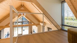 Une chambre mansardée avec des poutres apparentes, un plafond en verre et une vue sur l’extérieur.