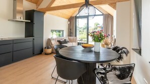 Une cuisine moderne dotée d’une grande fenêtre, un coin repas avec une table ronde et un espace salon confortable.