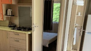 Et kompakt køkken med komfur, skabe og en lille spiseplads.
