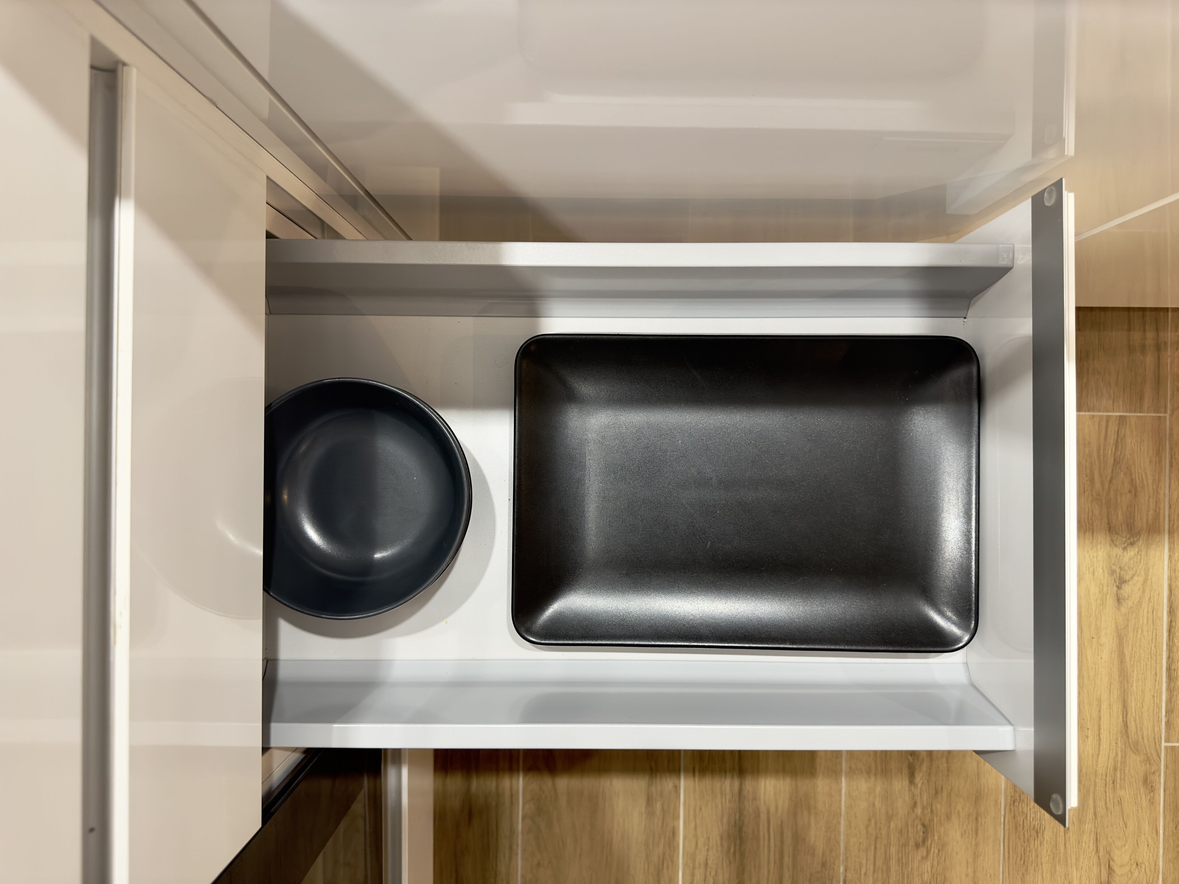 Un tiroir de cuisine contenant une poêle noire et une plaque de cuisson noire.