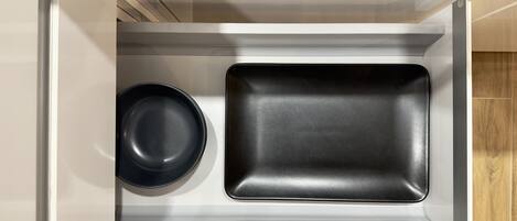 Un tiroir de cuisine contenant une poêle noire et une plaque de cuisson noire.