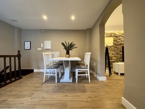 A dining area with a white table and chairs, a potted plant, and a stone accent wall. - Apartamento Anaya 3, en Pleno Centro de Granada (Granada)