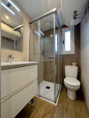 A modern bathroom with a glass-enclosed shower, a white toilet, and a vanity with a mirror. - Apartamento Anaya 3, en Pleno Centro de Granada (Granada)