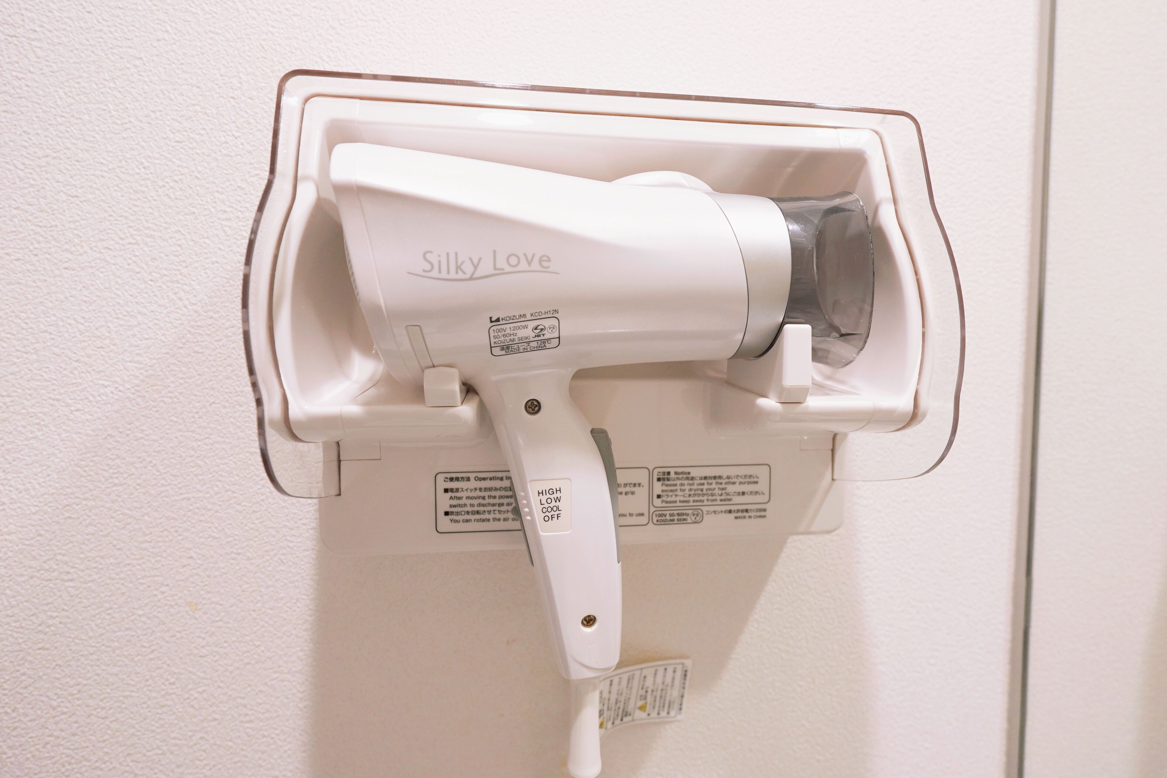 A hair dryer mounted on a wall, labeled "Silky Love," with operational instructions and safety warnings.