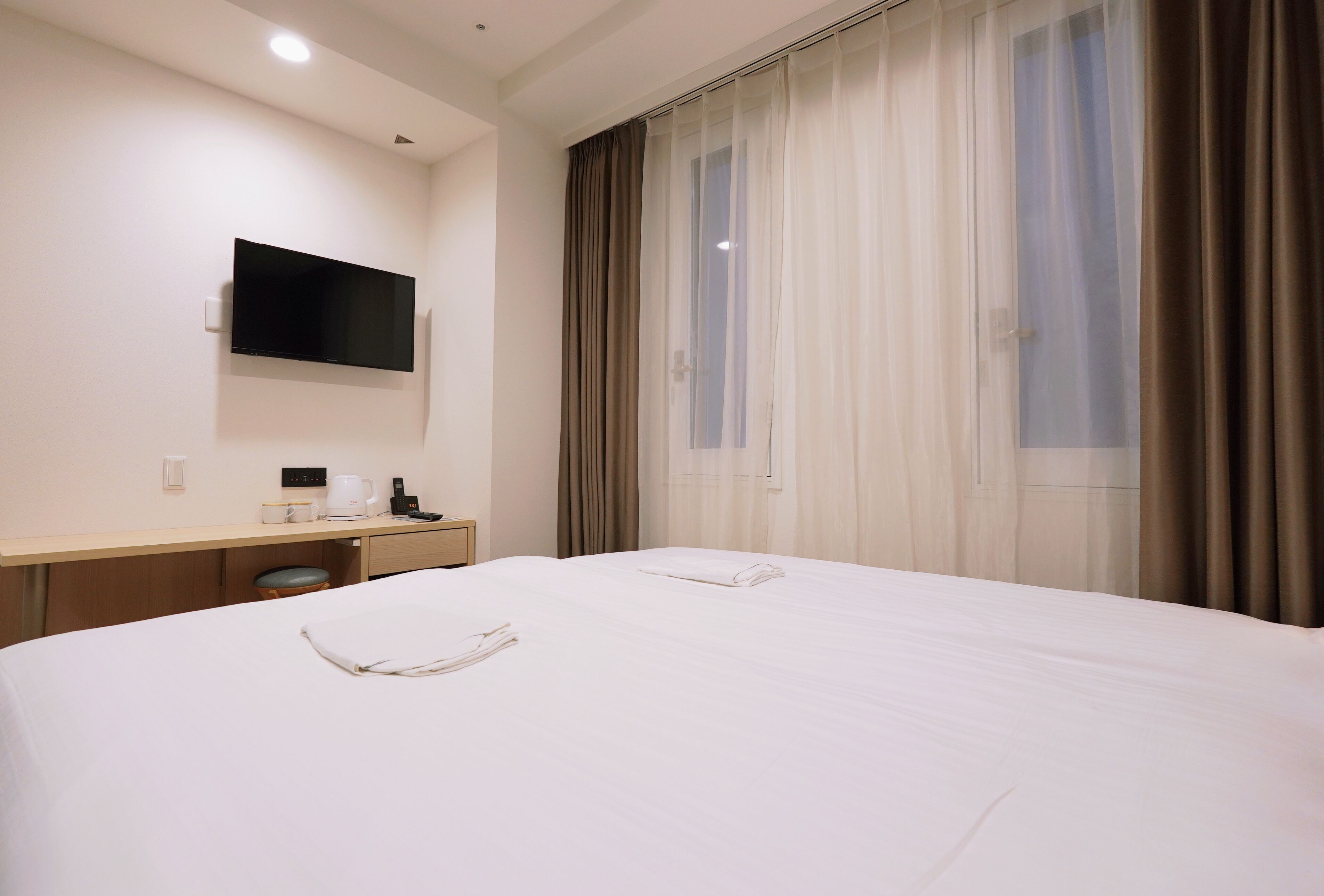 Een hotelkamer met een groot bed, een bureau met een flatscreen-tv, een koffiezetapparaat en een raam met gordijnen.
