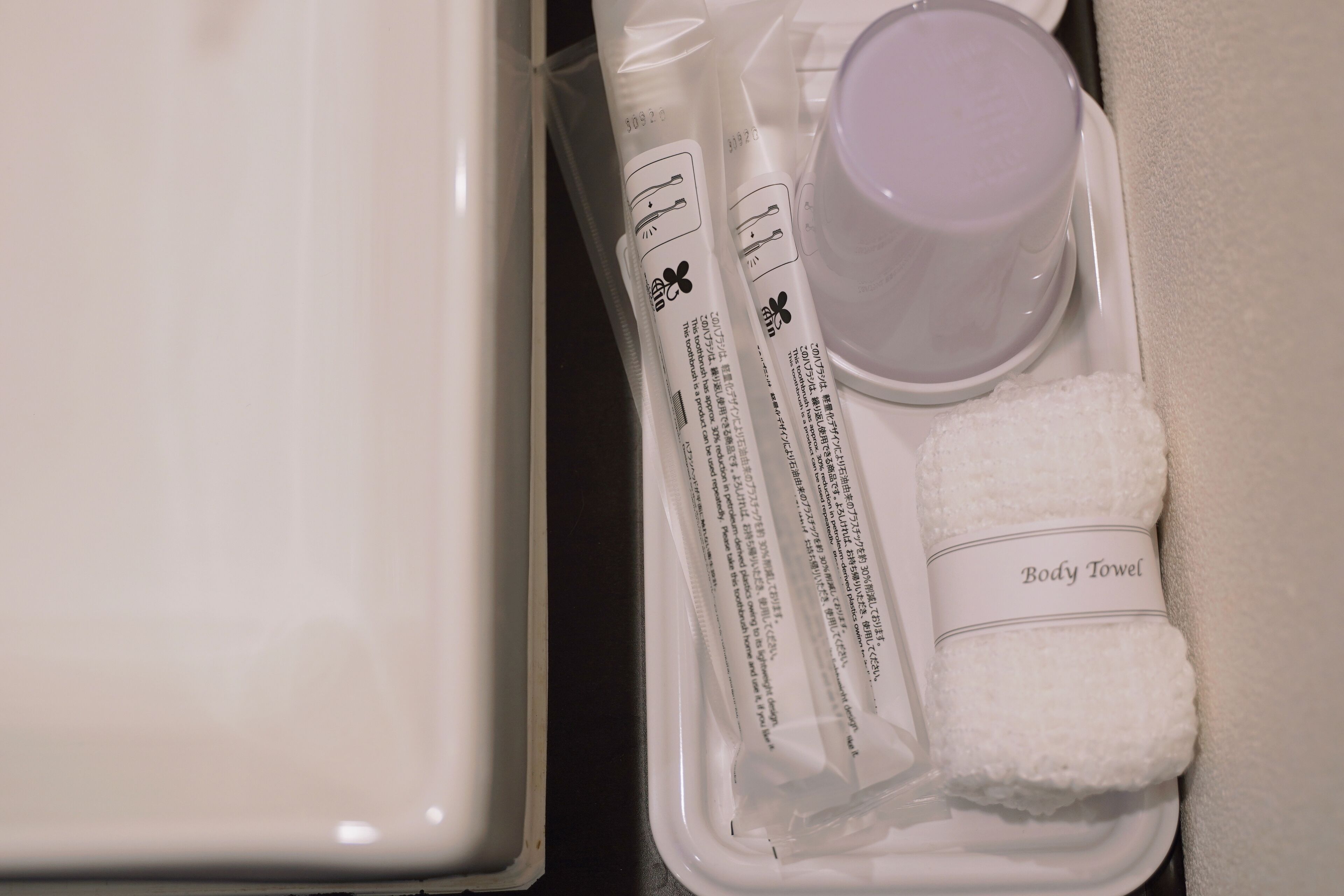 A bathroom with a white bathtub, a white body towel, and a white bottle of shampoo.