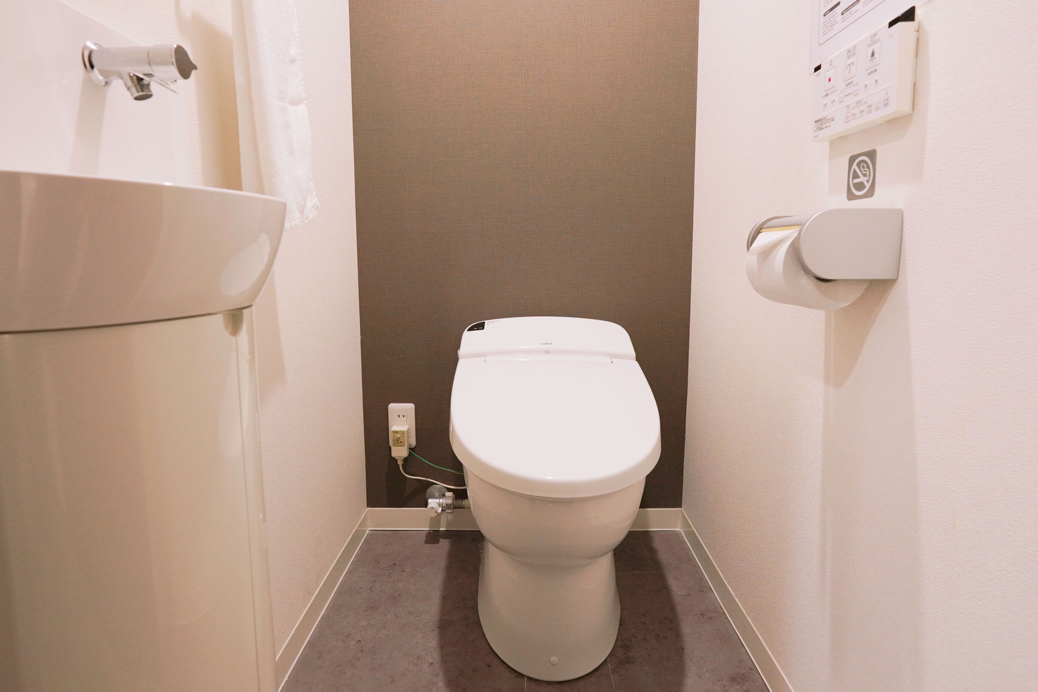A small bathroom with a white toilet, a sink, and a paper towel dispenser.