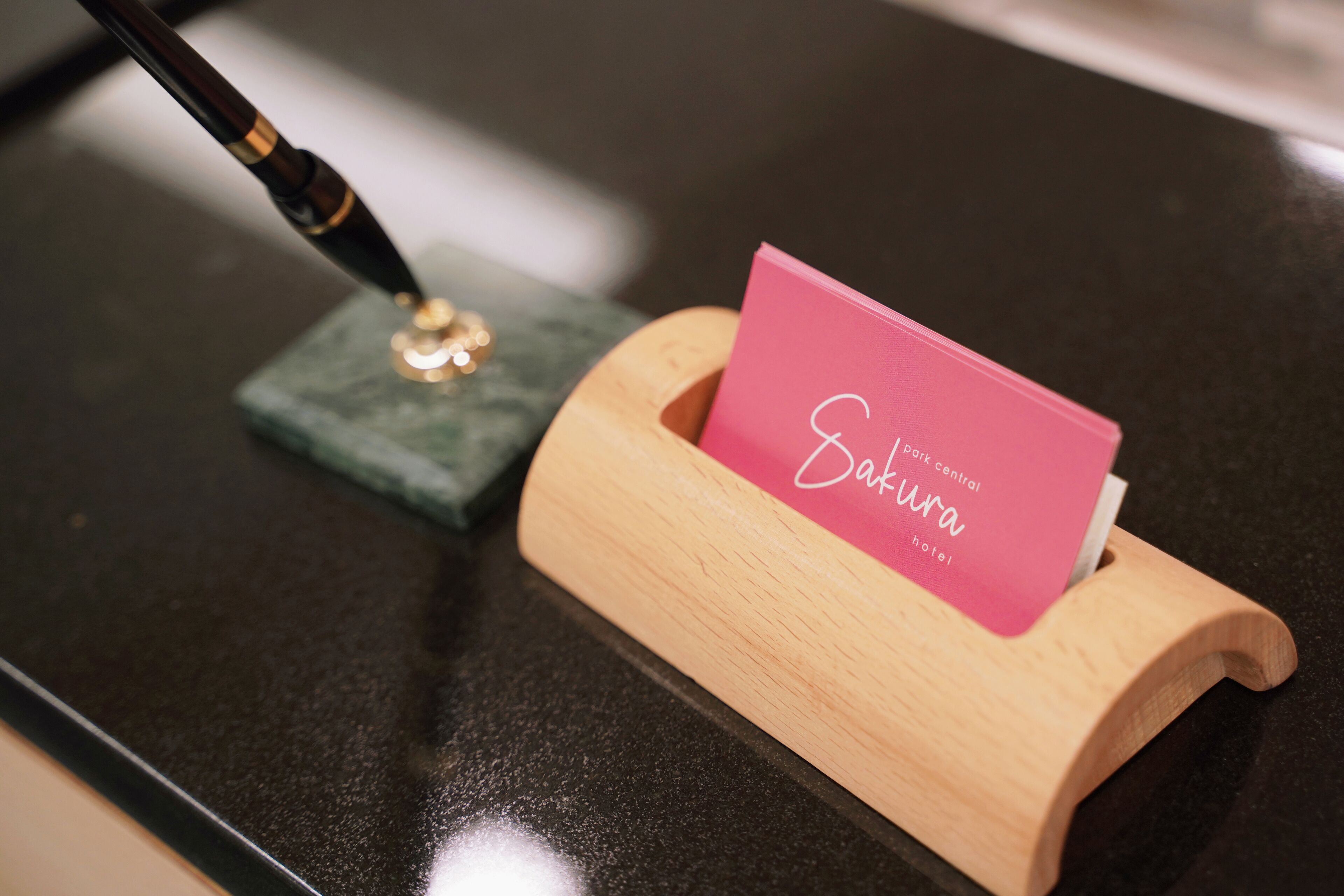 Un porta tarjetas de madera con una tarjeta rosa que dice "Sakura hotel".