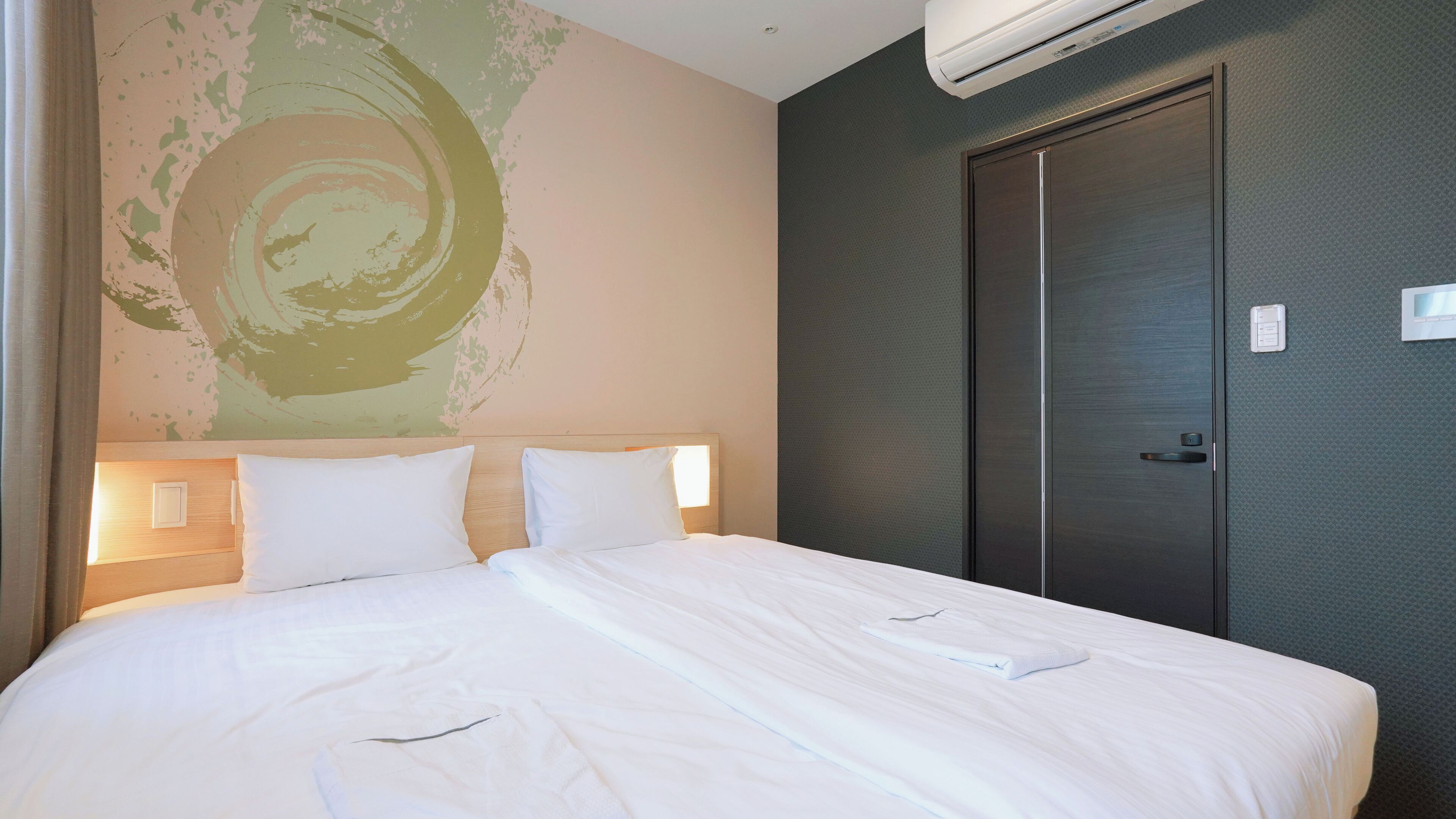 A hotel room with a large bed, a dark door, and a wall with a textured pattern.