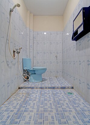 A bathroom with a toilet, shower, and a wall-mounted mirror. - Hotel O Lavina Guesthouse (Dumai)