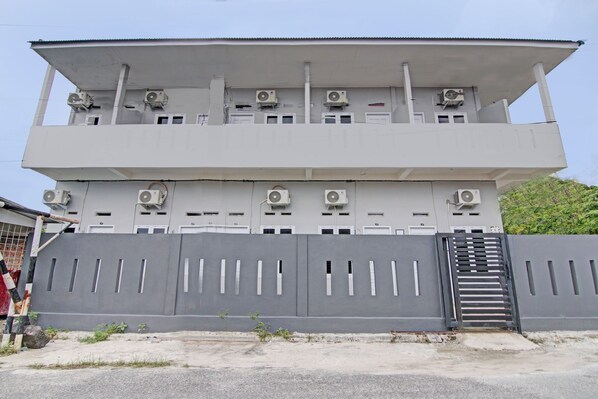 A multi-story building with air conditioning units and a gated entrance. - Hotel O Lavina Guesthouse (Dumai)