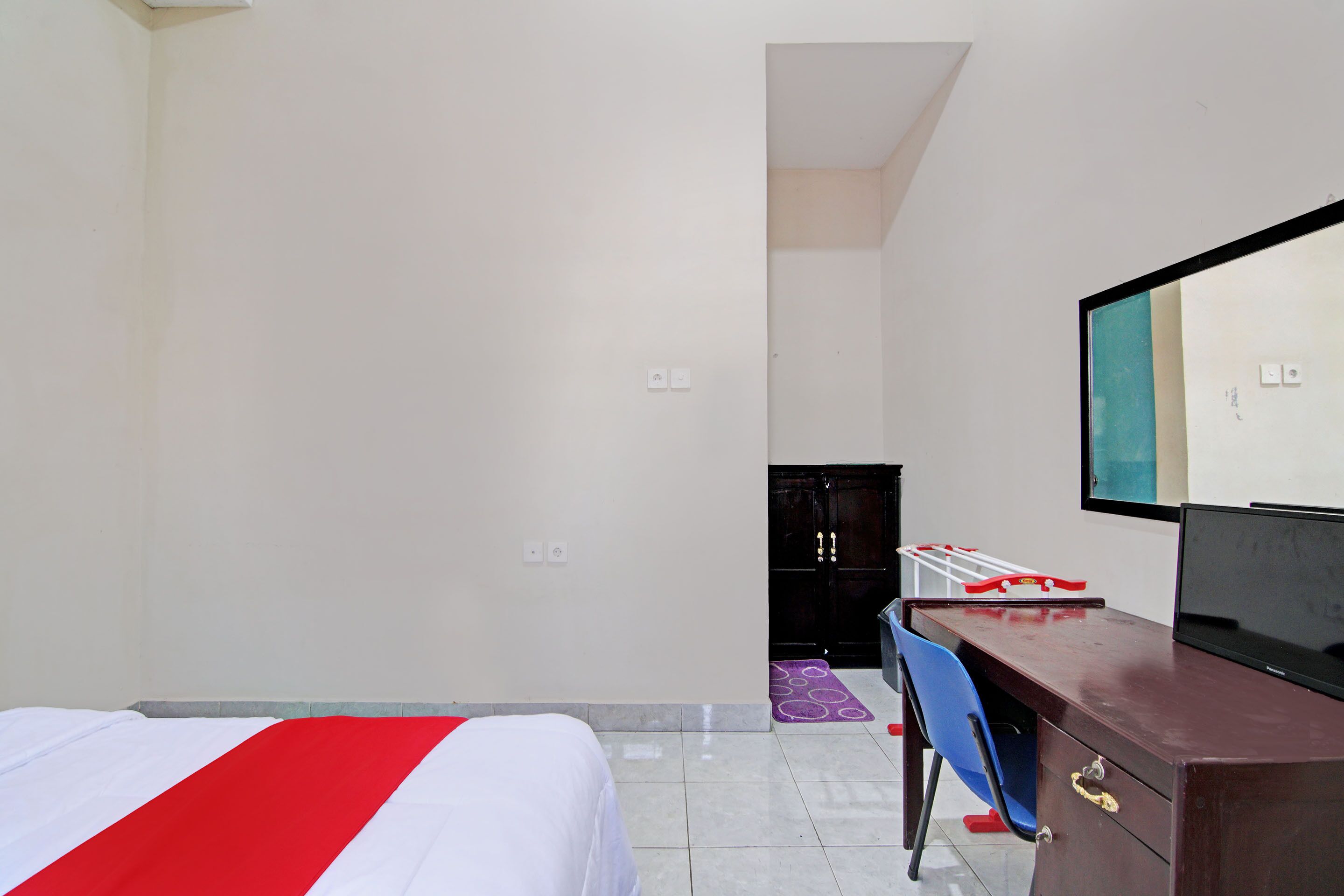 Ein Hotelzimmer mit einem Bett, einem Schreibtisch, einem Sessel, einem Fernseher und einem Kleiderschrank.