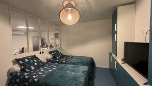 Ett sovrum med två sängar, en stor spegel, en tv och en taklampa.