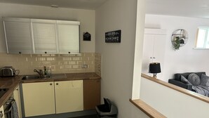 Una cucina moderna con lavello, tostapane e pensili. Si nota un cestino e un cartello con il menu delle bevande calde al caffè appeso al muro.
