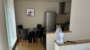 Un angolo cottura compatto con frigorifero, microonde e una ventola su un piano di lavoro in legno.
