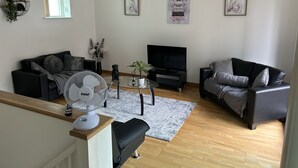 Un soggiorno moderno con due divani, una televisione e un ventilatore.