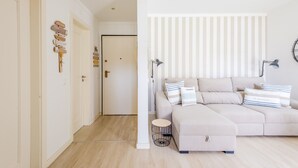 A modern living room with a beige sofa, striped pillows, and a round side table.