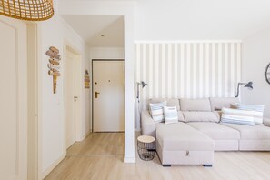 Un salon moderne avec un canapé beige, des coussins à rayures et une petite table d’appoint ronde.