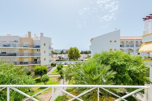 A residential area with modern buildings, a clear sky, and lush greenery.