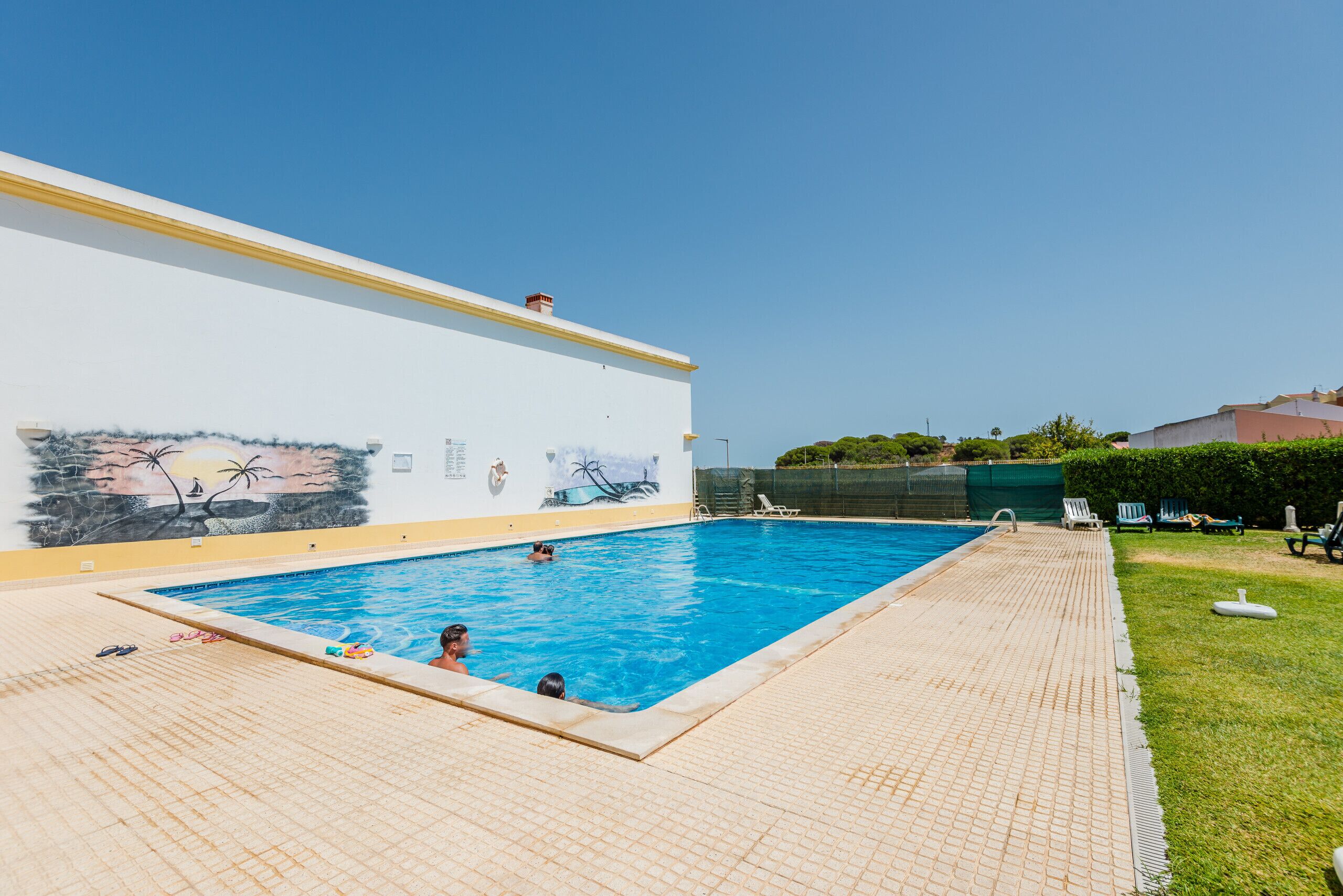 A swimming pool with a tiled deck and a mural on the adjacent wall.