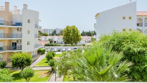 A residential area with multi-story buildings, a central tree, and a parking area.