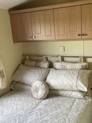 Un dormitorio con cama, ropa de cama estampada, cabecera y armarios de madera arriba.