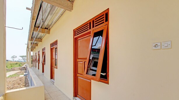 Un couloir doté d’un sol carrelé, de portes en bois et d’une fenêtre donnant sur l’extérieur.
