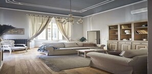 Una sala de estar con un sofá, sillones, una mesa de centro y una estantería.