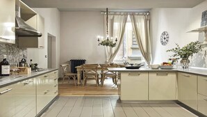 A modern kitchen with a central island, wooden chairs, a dining table, and a built-in stove. - The style of Italian luxury close to the Duomo
 (Firenze)