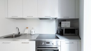 Ett modernt kök med vitvaror i rostfritt stål, en vattenkokare och en mikrovågsugn.