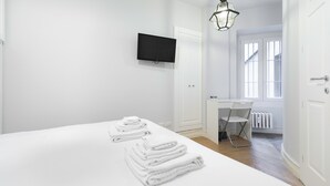 Ett hotellrum med en säng, ett skrivbord, en stol, en tv och ett fönster.