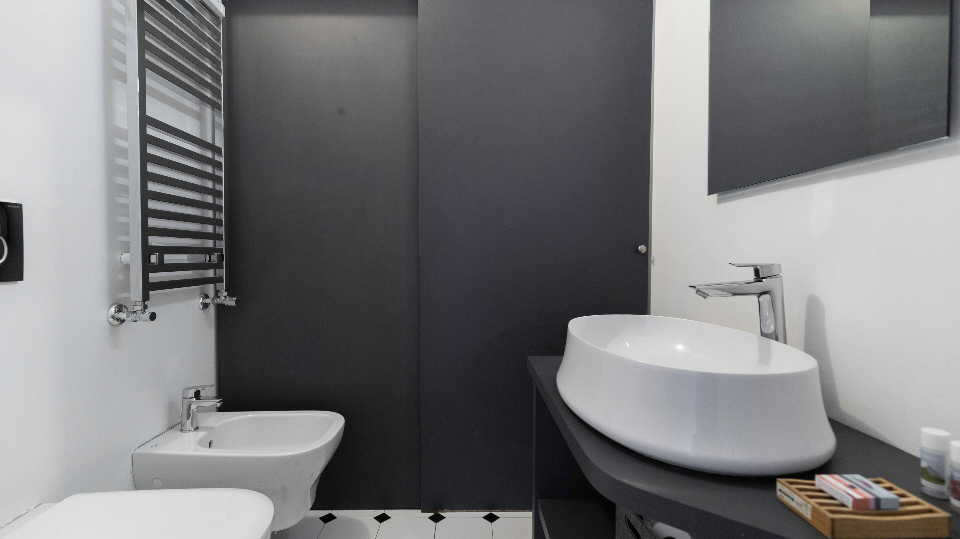 A modern bathroom with a large white sink, a bidet, and a toilet.