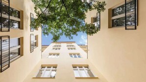 Ein Flur mit Blick auf ein Gebäude mit zahlreichen Fenstern und einem Baum darüber.