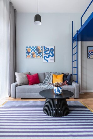 A modern living room with a grey sofa, a black coffee table, and two framed artworks on the wall.