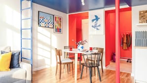 A modern living space with a loft area, a dining table with chairs, a sofa, and a coffee table. - TurnKey | Charles Square Studio – with Terrace (Praha 2)