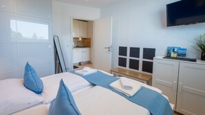 Une chambre d’hôtel moderne équipée d’un lit, d’une télévision, d’une kitchenette et offrant une vue sur la ville.