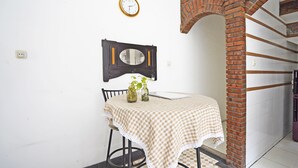 A small dining area with a checkered tablecloth, a wall clock, and a vintage mirror. - Hotel O Kost Putih Syariah (Blitar)