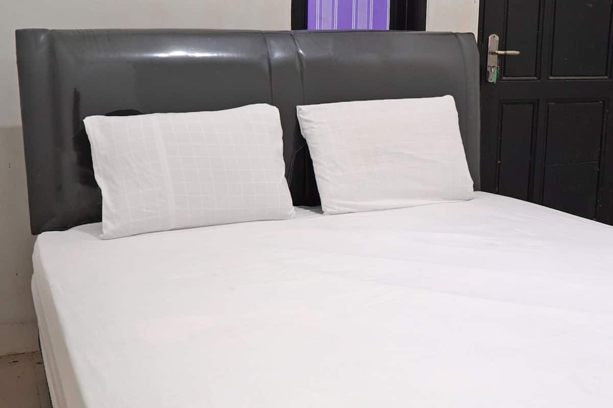 A bed with a dark headboard and two white pillows.