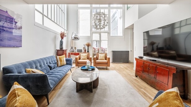 Un salon spacieux avec une grande télévision, un canapé bleu et un meuble rouge.