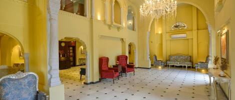 A grand lobby with a chandelier, classical architecture, and a star-patterned floor.