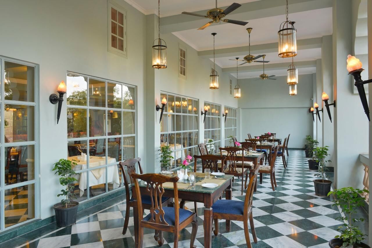 A dining area with tables and chairs, large windows, and hanging lanterns.