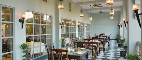 A dining area with tables and chairs, large windows, and hanging lanterns.