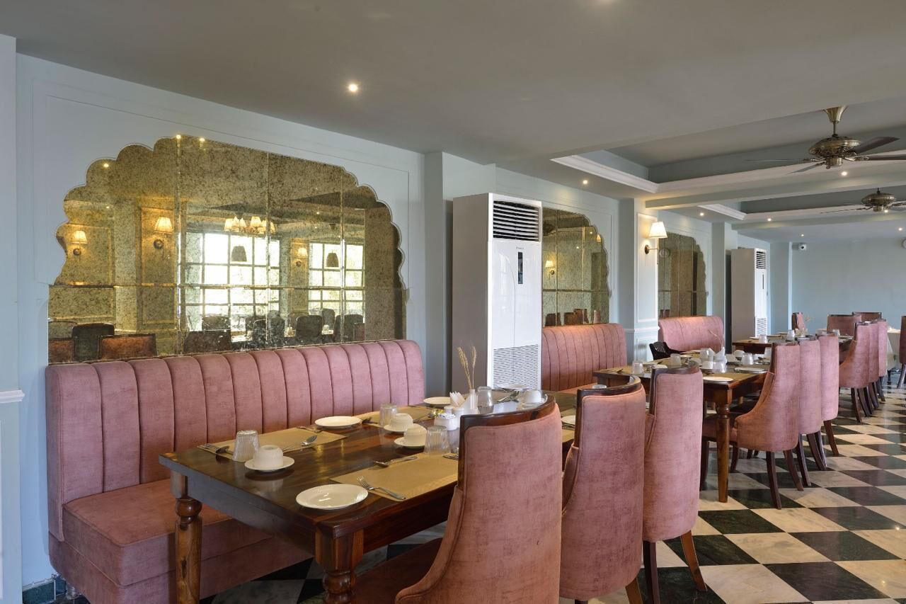 A restaurant with a checkered floor, pink upholstered booths, and a large mirror with a decorative frame.