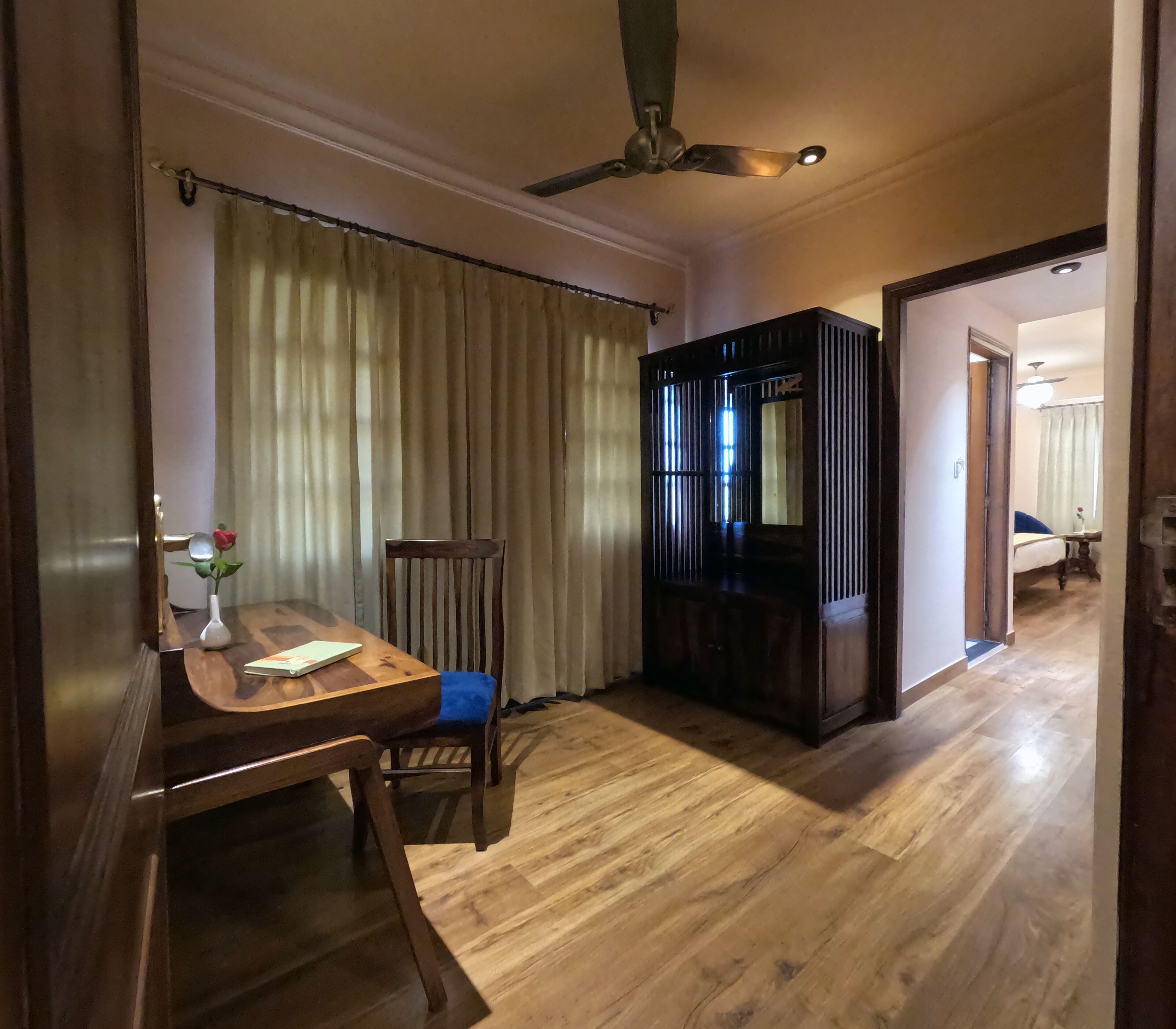 Una habitación con una mesa de comedor de madera, una silla, un ventilador de techo y un mueble de madera oscura.