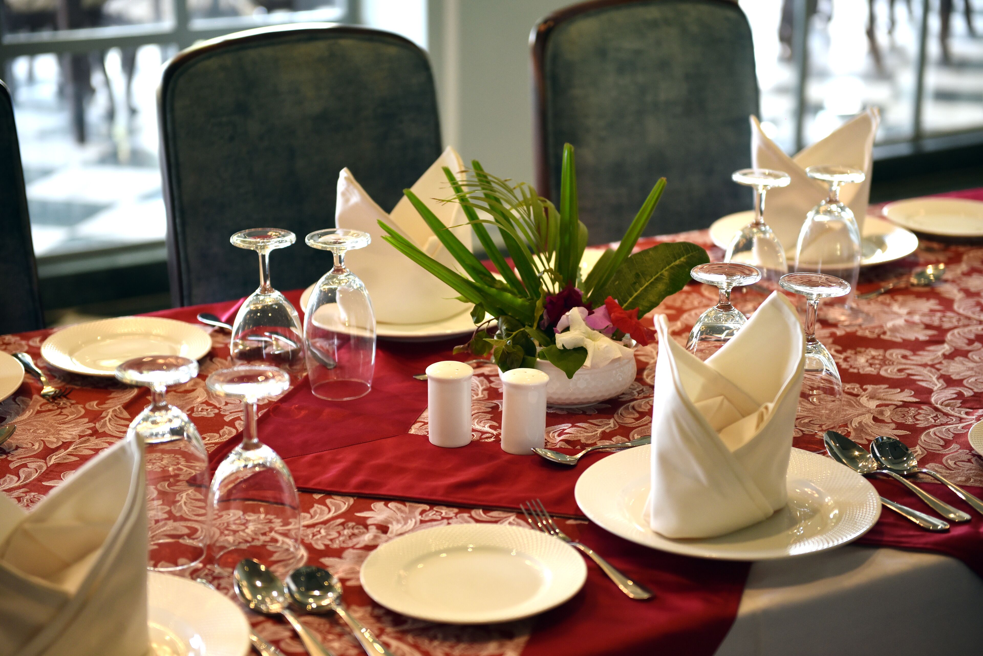 A table set for dining with white plates, silverware, and wine glasses.