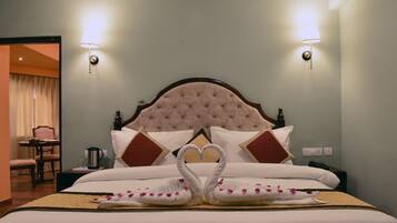 A hotel room with a large bed, two wall-mounted lamps, a nightstand, a chair, and a table.