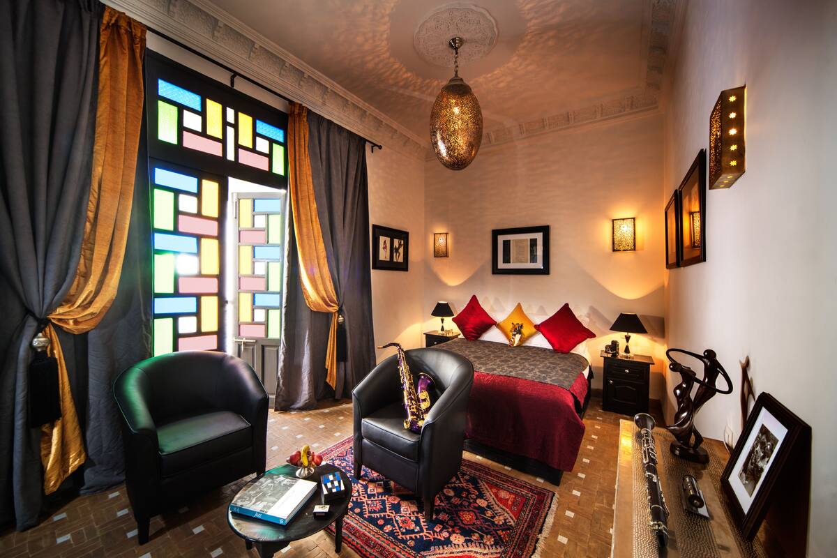 A hotel room with a bed, a sofa, a desk, and a lamp.