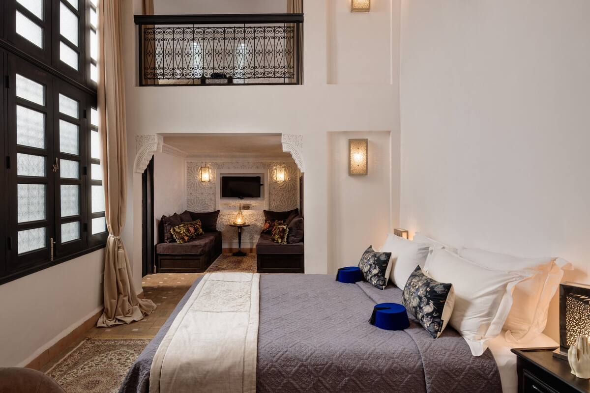 A spacious bedroom with a large bed, a sofa, and a balcony.
